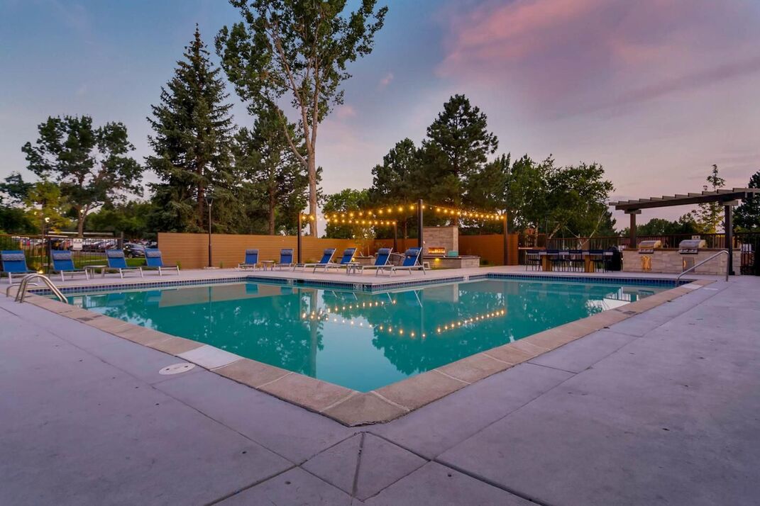 Luxury swimming pool and grilling station with hanging lights at dusk in Denver. Colorado