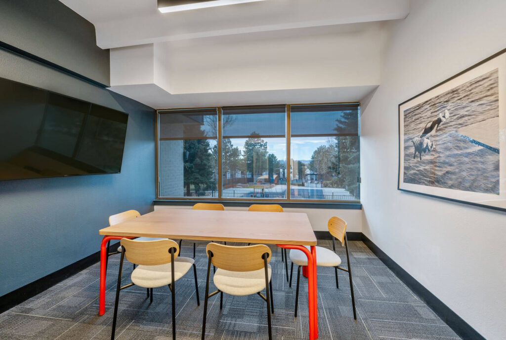 office space with table and chairs in a room with a television on the wall and large windows