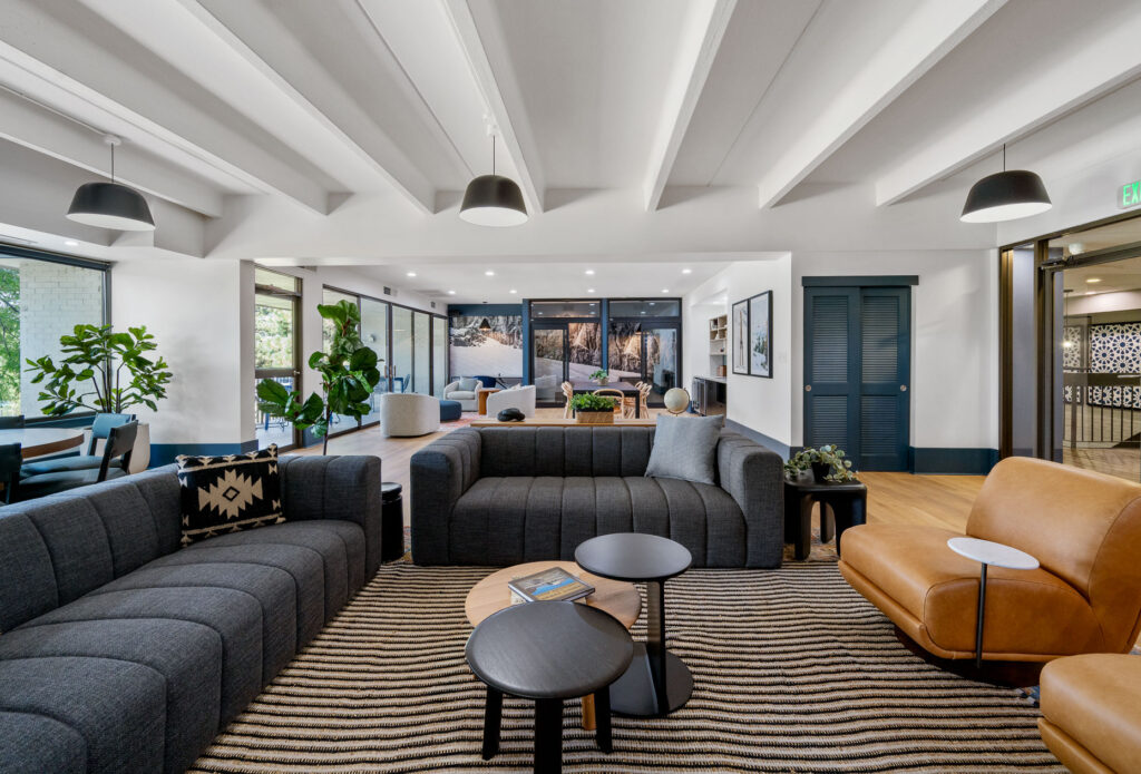 Elm at Panorama clubhouse seating space with sofas and armchair seating in a room with overhead and natural lighting